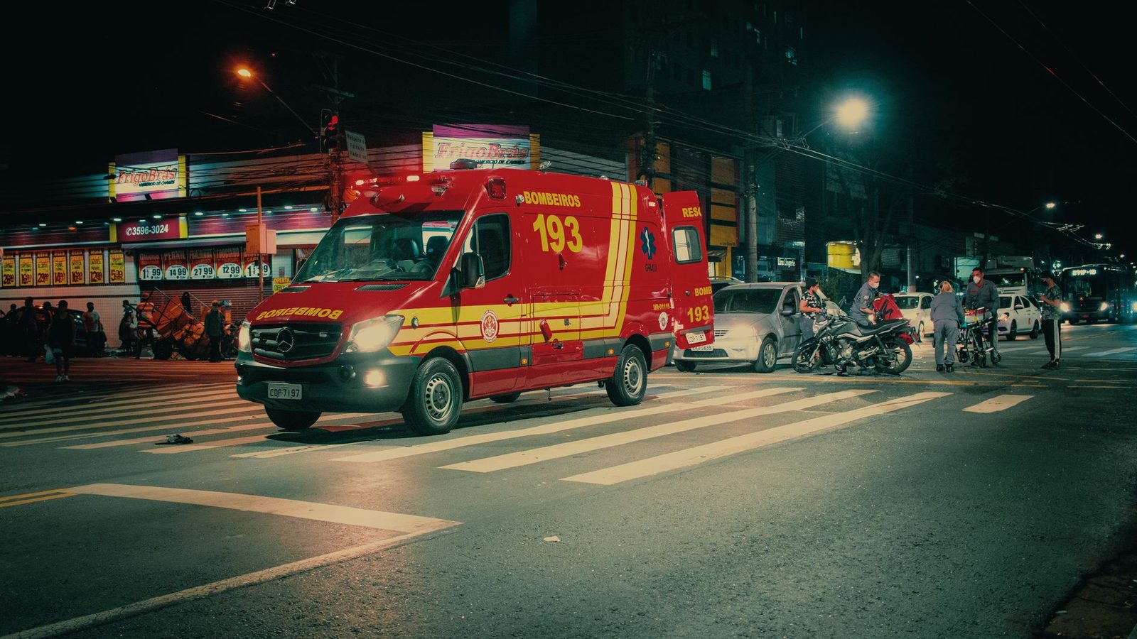 An emergency vehicle attending a crash on a city street at night.