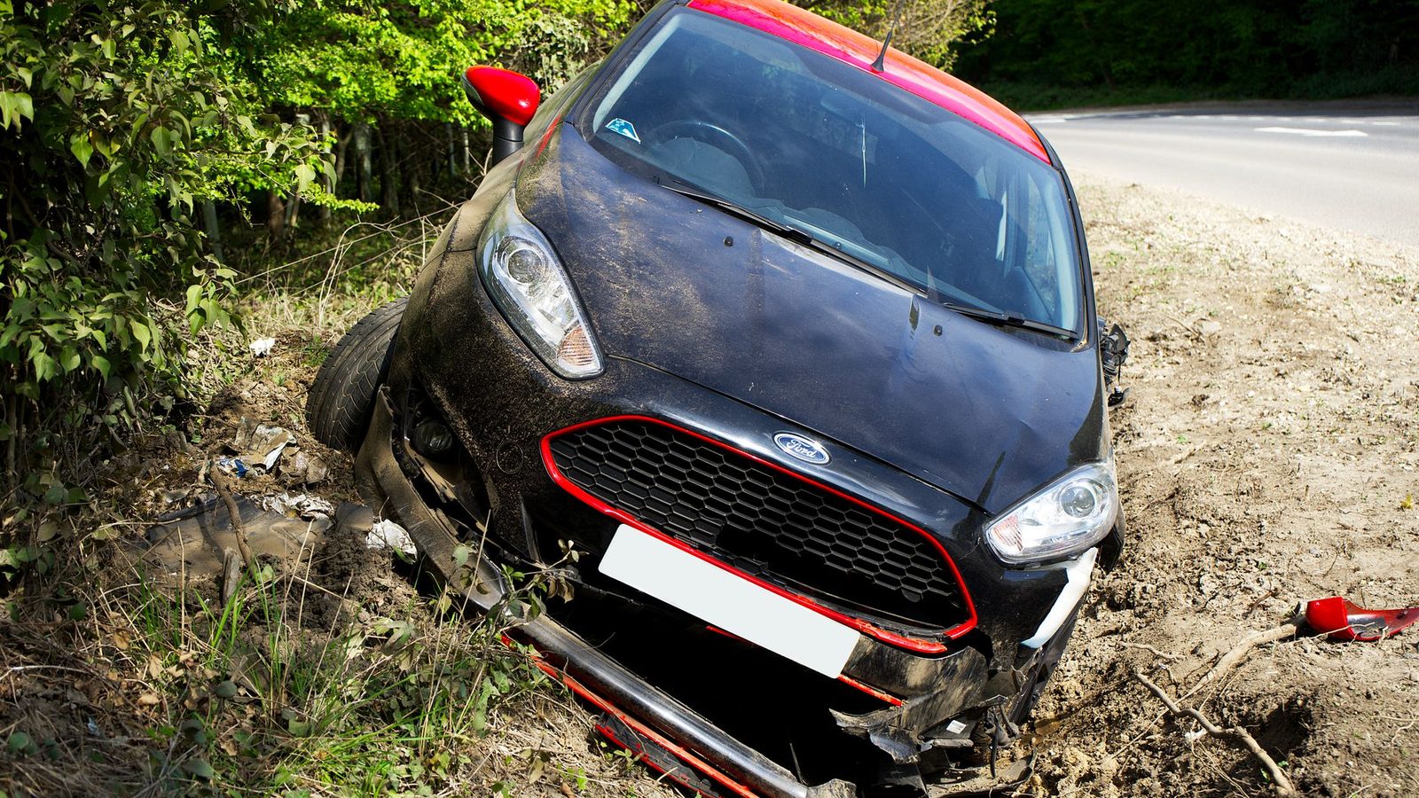 A car left in a roadside ditch after a collision.