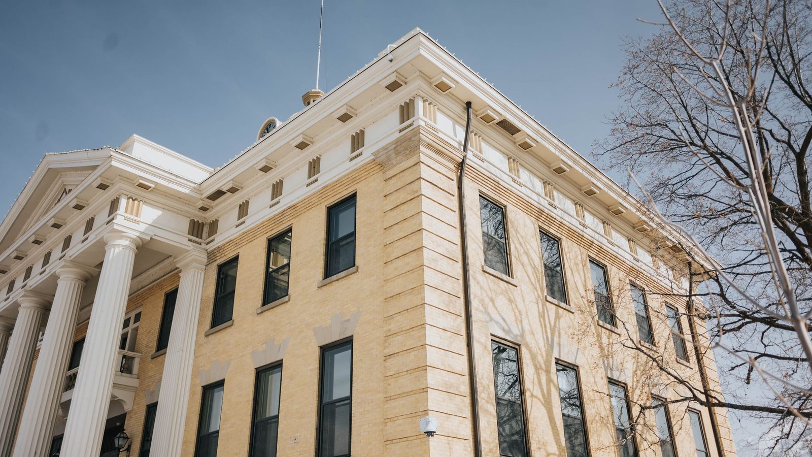 The columned facade of a historic county courthouse against a blue sky.
